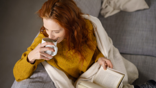 Женщина читает книгу и пьет чай