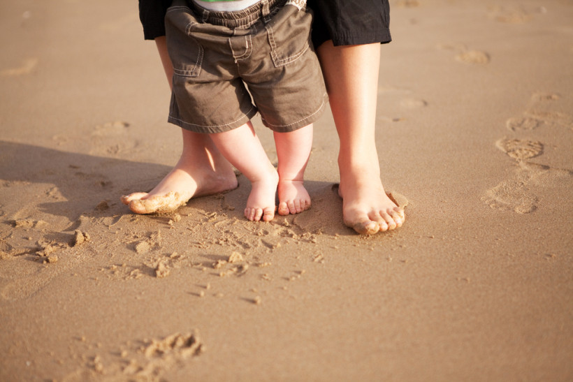 Ножки ребенка и папы на песке 