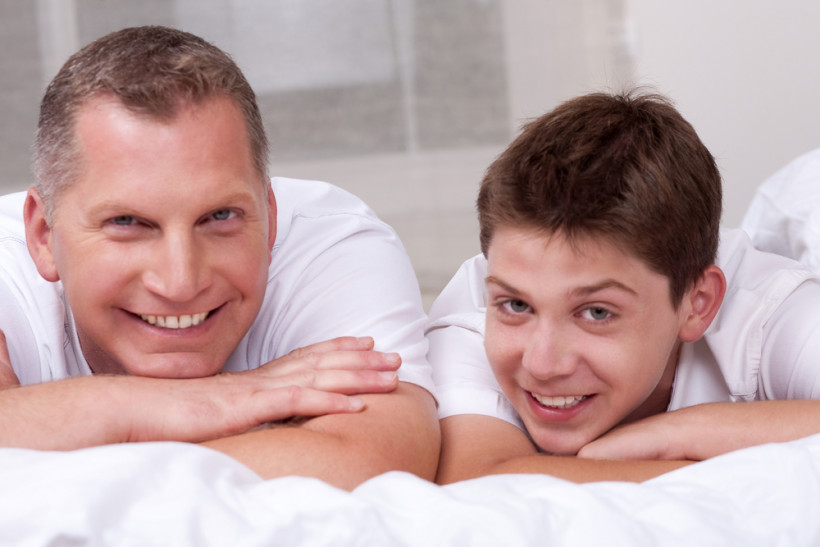 Папа и подросток лежат на кровати 