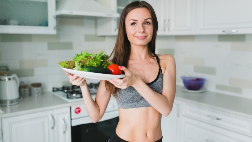 Девушка держит тарелку с овощами