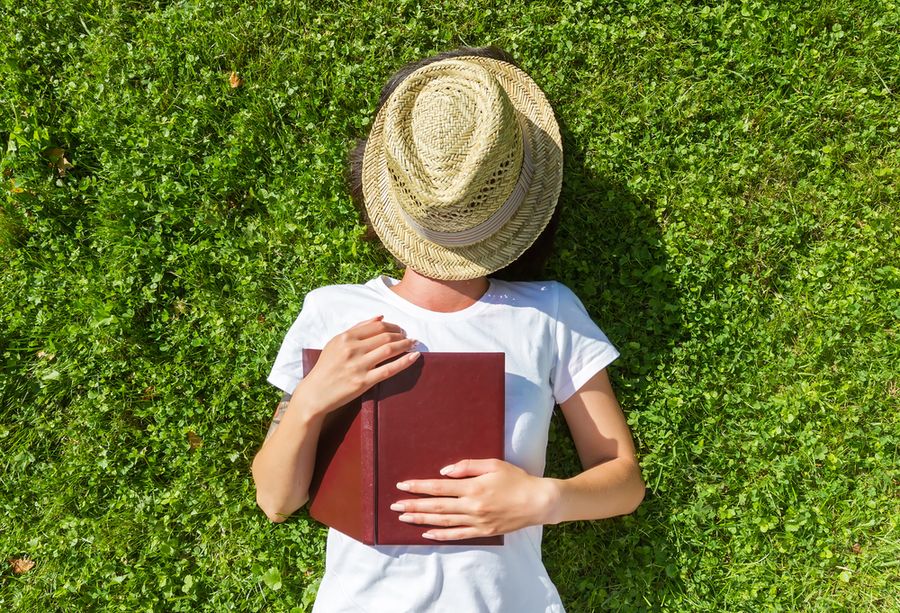 жінка лежить на траві з книгою, овуляція