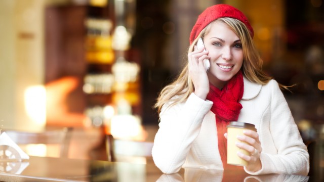 Девушка разговаривает по телефону в кафе