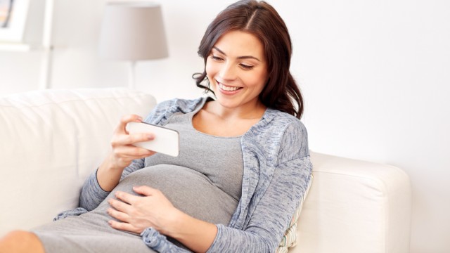 Беременная женщина держит смартфон в руках