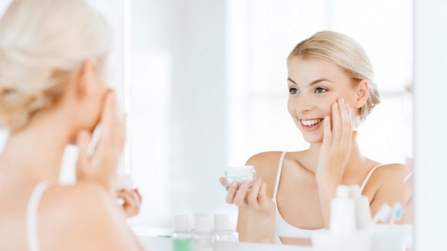 Девушка наносит крем на лицо