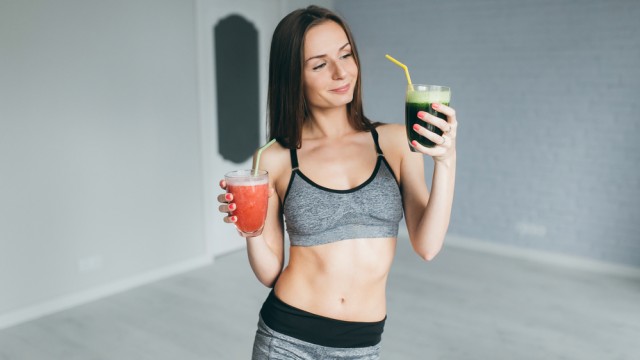 Спортивна дівчина тримає стакани з коктейлями