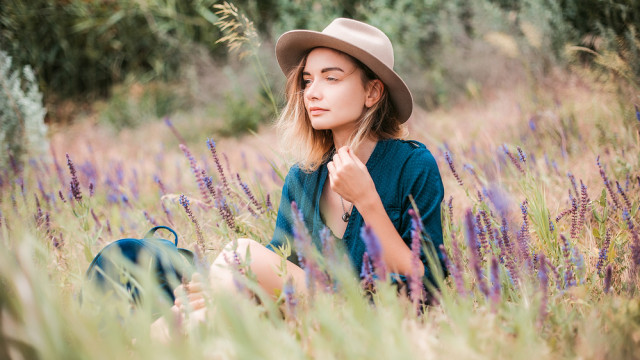 Дівчина в капелюсі сидить у полі