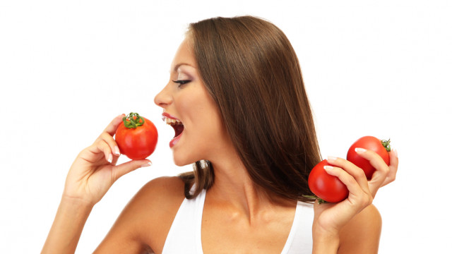 жінка їсть помідор