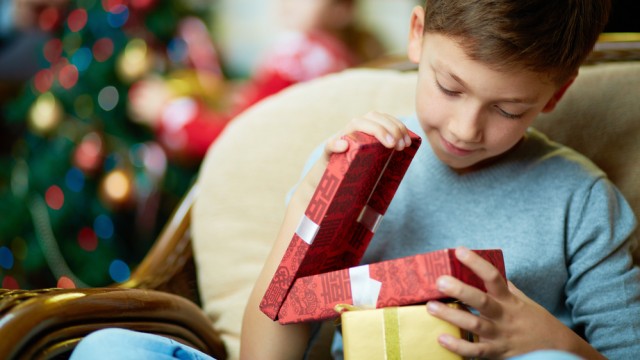 мальчик смотрит подарок на Новый год