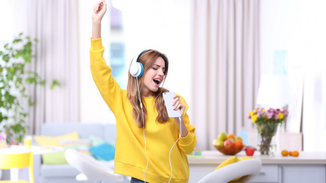 Девушка в желтом свитере слушает музыку