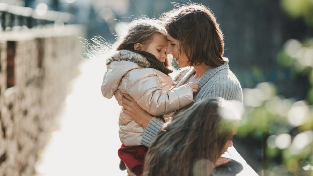 Мама обнимает маленькую дочку на улице