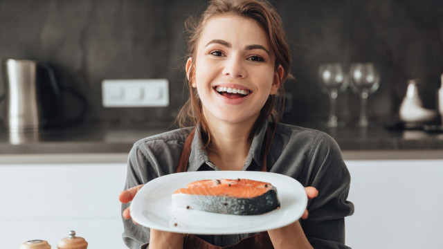 Дівчина тримає тарілку з лососем