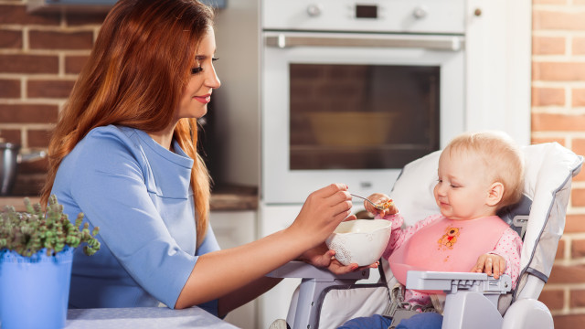 Мама кормит ребенка с ложечки