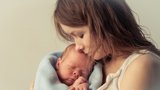 Мама держит младенца на руках и целует