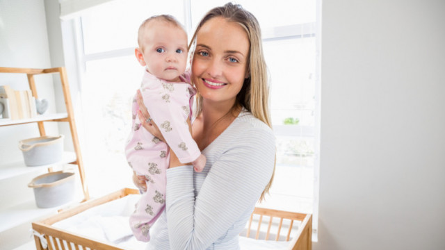 мама-блондинка держит ребенка на руках