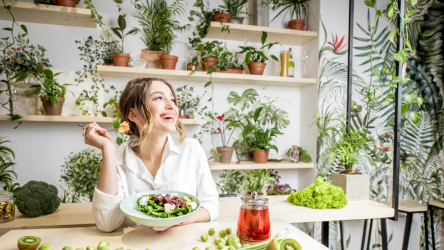 дівчина їсть на фоні рослин