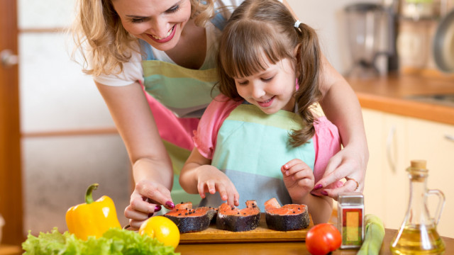 мама с дочкой готовят рыбу