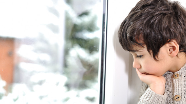ребенок грустит перед окном зимой